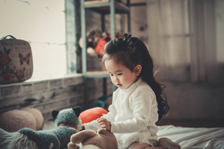 عکس دختر بچه کوچولو چینی در حال بازی با عروسک